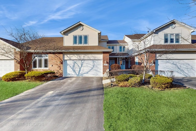 traditional-style home with an attached garage, driveway, a front yard, and brick siding