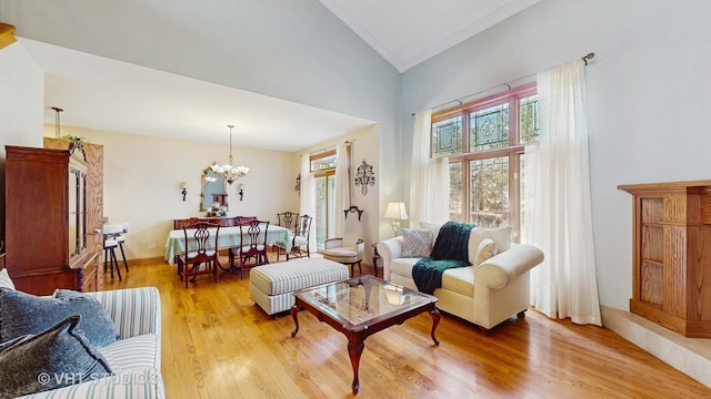 living room with an inviting chandelier, ornamental molding, high vaulted ceiling, light wood-type flooring, and baseboards