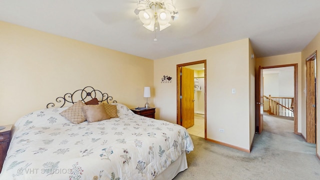 bedroom with baseboards, ensuite bathroom, a ceiling fan, and light colored carpet