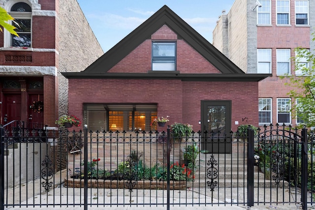 view of front of house featuring brick siding, a fenced front yard, and a gate