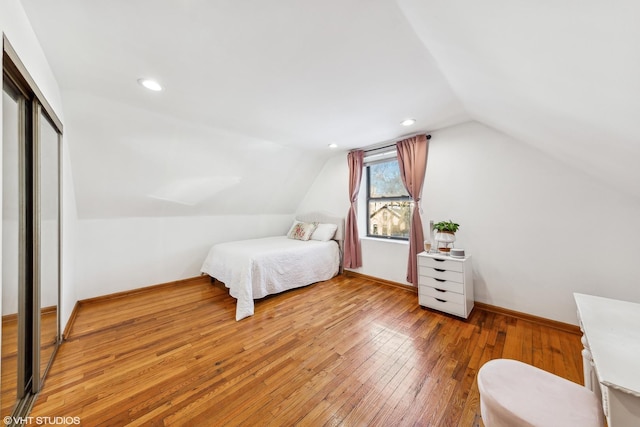 bedroom with recessed lighting, wood finished floors, baseboards, vaulted ceiling, and a closet