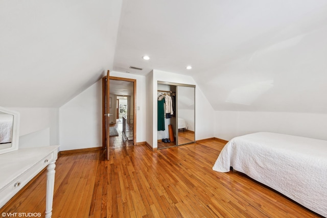 bedroom featuring lofted ceiling, visible vents, baseboards, a closet, and light wood finished floors