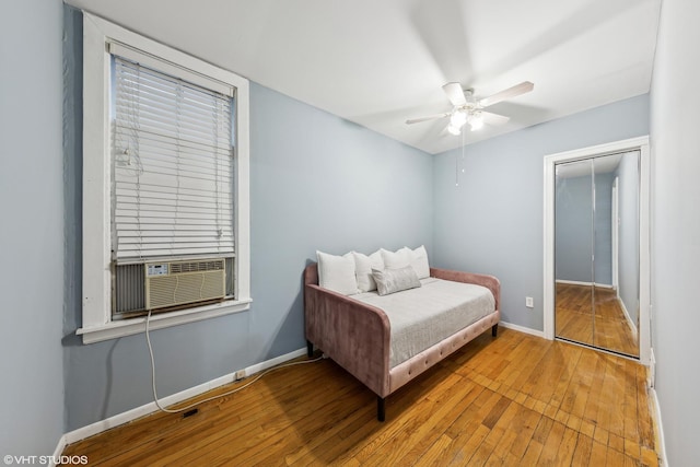 bedroom with light wood finished floors, a ceiling fan, baseboards, and cooling unit