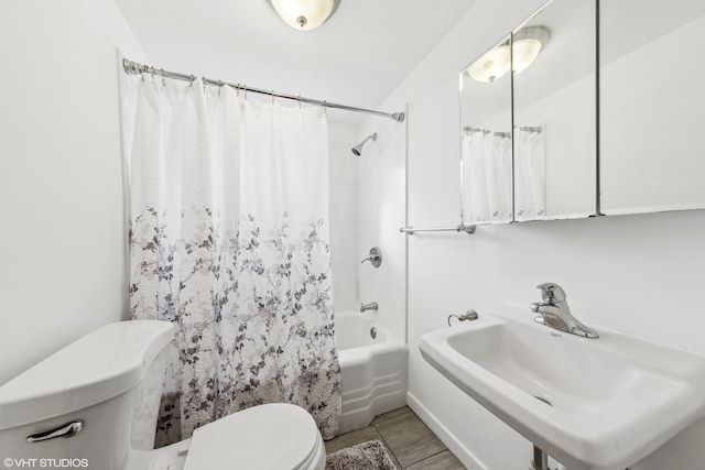 bathroom with shower / bath combo with shower curtain, a sink, and toilet