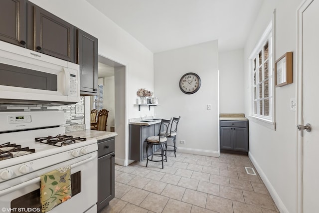 kitchen featuring dark brown cabinetry, white appliances, visible vents, light countertops, and decorative backsplash