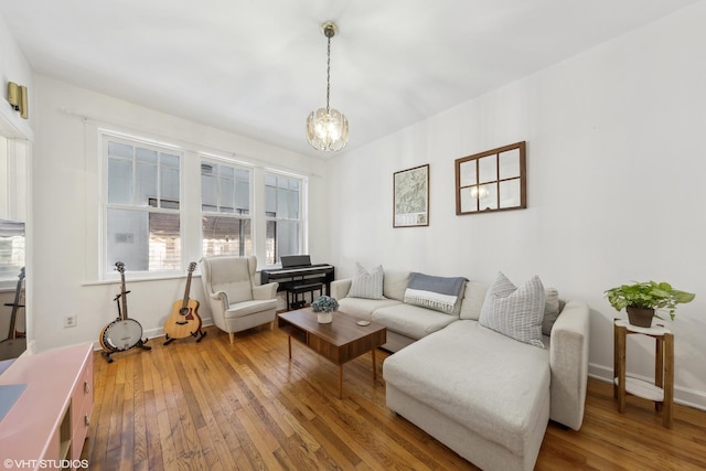 living room with baseboards, wood finished floors, and an inviting chandelier