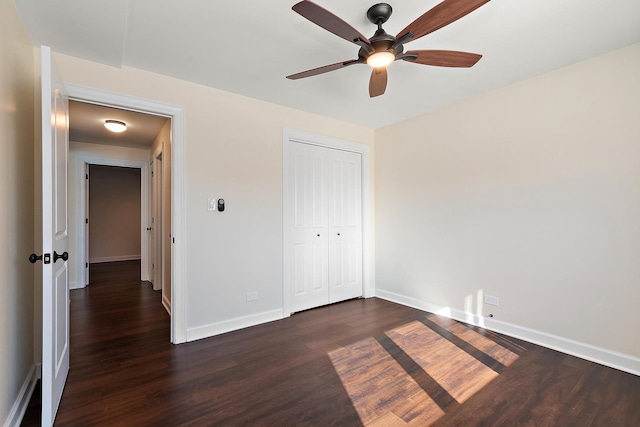 unfurnished bedroom featuring dark wood-style floors, ceiling fan, baseboards, and a closet