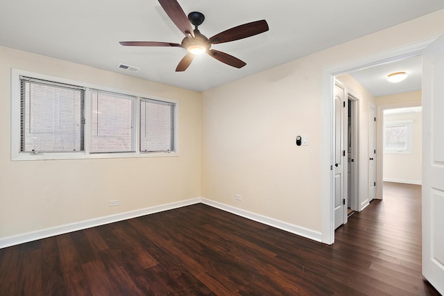 unfurnished room with a ceiling fan, dark wood-style flooring, visible vents, and baseboards