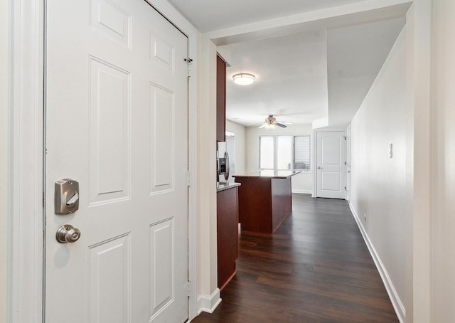 corridor with dark wood-style floors and baseboards