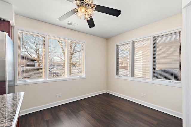 spare room with baseboards, visible vents, ceiling fan, and dark wood-type flooring