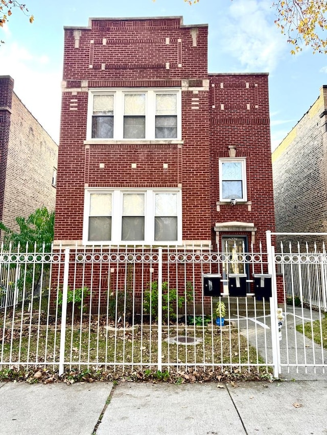 view of front of home with a fenced front yard, a gate, and brick siding