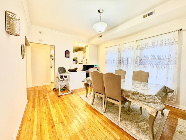 dining room with baseboards, crown molding, visible vents, and wood finished floors