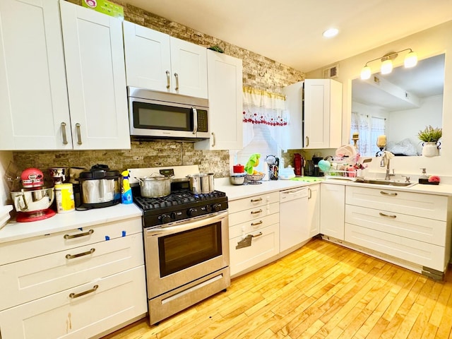 kitchen featuring light countertops, appliances with stainless steel finishes, a sink, and white cabinets