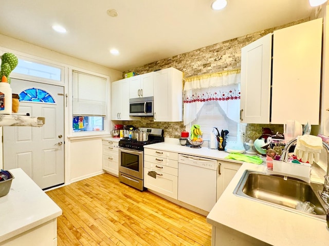 kitchen with a sink, stainless steel appliances, light countertops, and white cabinets