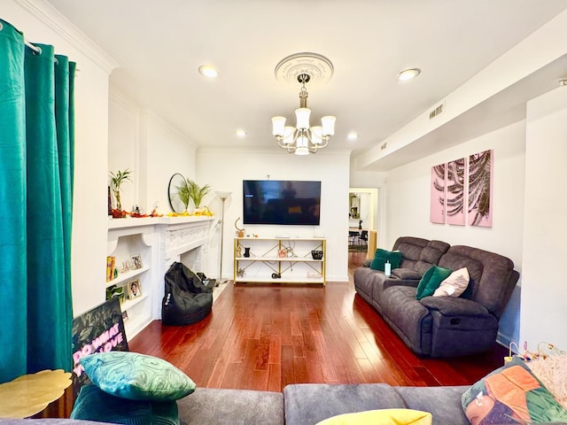 living room with dark wood finished floors, visible vents, a fireplace with raised hearth, an inviting chandelier, and ornamental molding