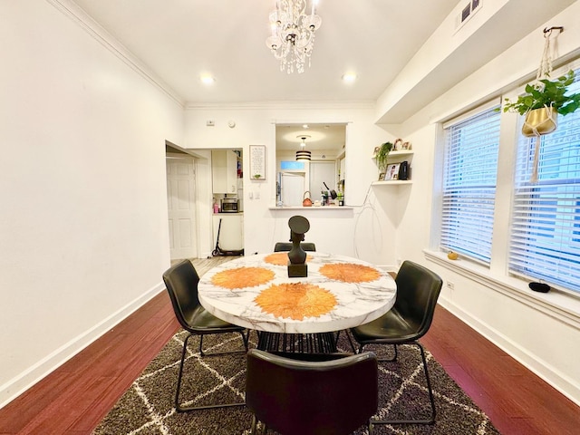 dining space with a chandelier, wood finished floors, visible vents, baseboards, and crown molding