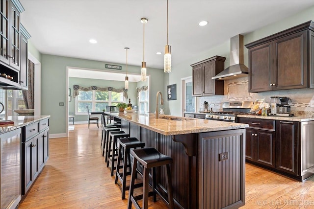 kitchen featuring wine cooler, a sink, stainless steel gas range, wall chimney exhaust hood, and tasteful backsplash