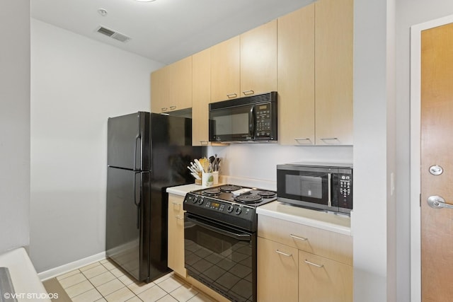 kitchen with black appliances, light countertops, light brown cabinets, and visible vents