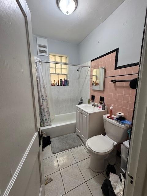 full bathroom featuring tile patterned flooring, toilet, tile walls, vanity, and shower / tub combo with curtain