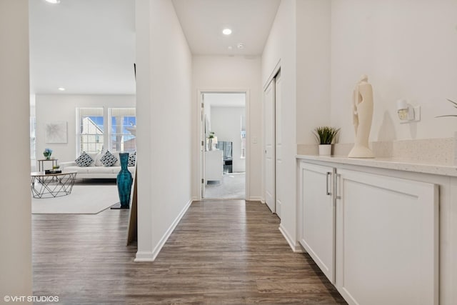 corridor with dark wood-style floors, baseboards, and recessed lighting