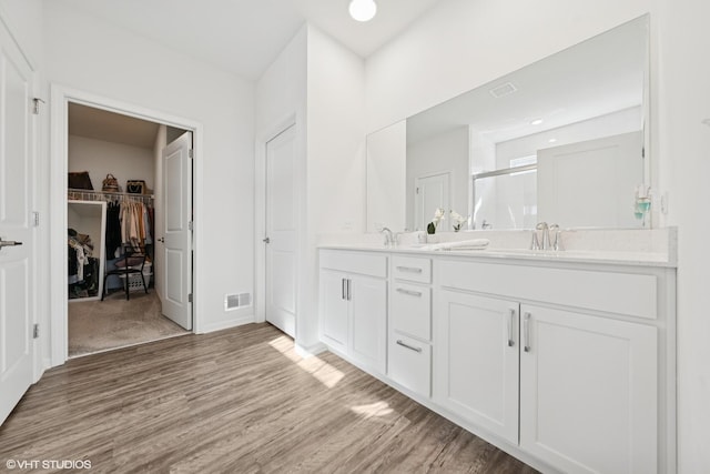 full bathroom with visible vents, wood finished floors, a spacious closet, vanity, and a shower stall