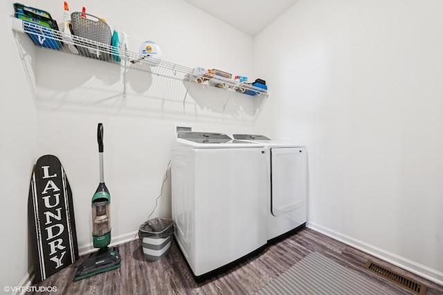 clothes washing area featuring washing machine and dryer, laundry area, wood finished floors, visible vents, and baseboards