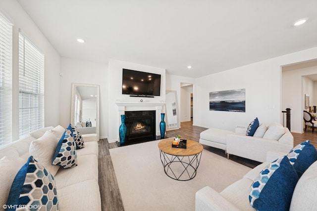 living area featuring a fireplace with flush hearth, recessed lighting, baseboards, and wood finished floors