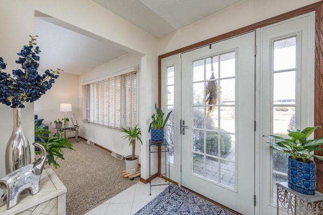 entryway with visible vents, plenty of natural light, light carpet, and light tile patterned floors