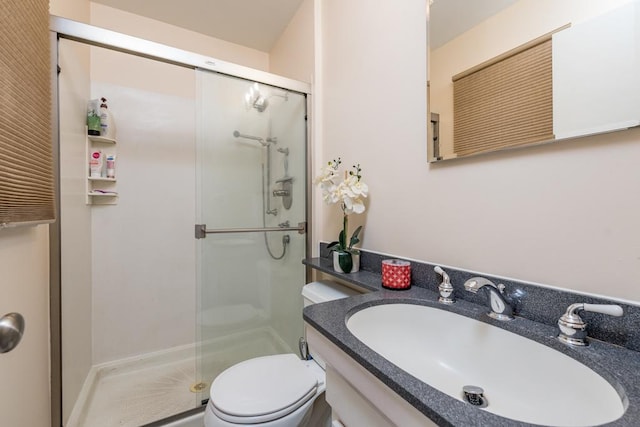 full bathroom featuring a stall shower, vanity, and toilet