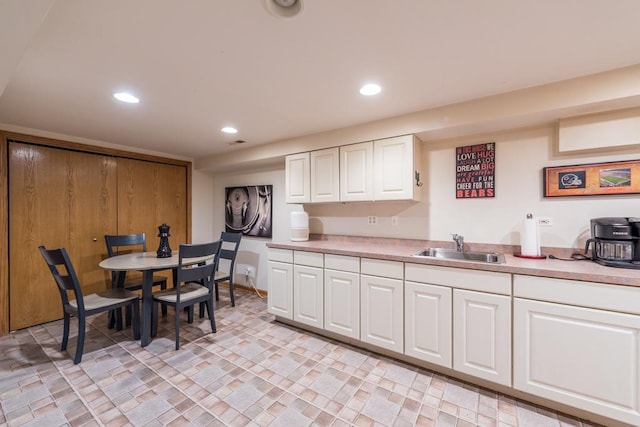 kitchen with light countertops, white cabinets, a sink, and recessed lighting