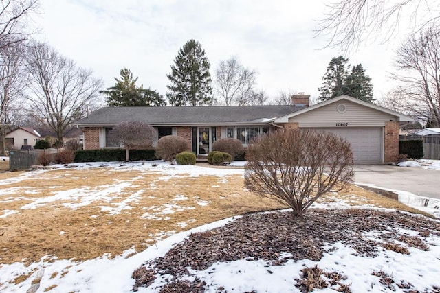 ranch-style home with brick siding, a chimney, fence, a garage, and driveway