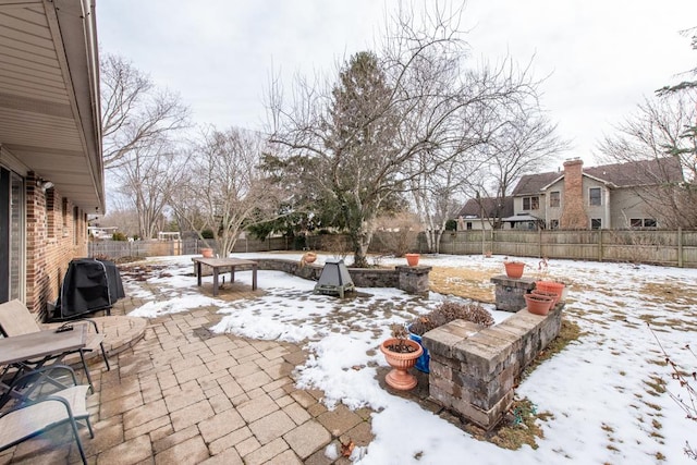 snow covered patio with a fenced backyard and a grill