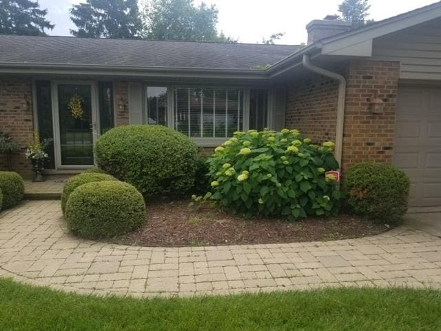 entrance to property featuring a garage and brick siding