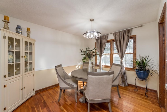 dining space featuring a textured ceiling, hardwood / wood-style flooring, and an inviting chandelier