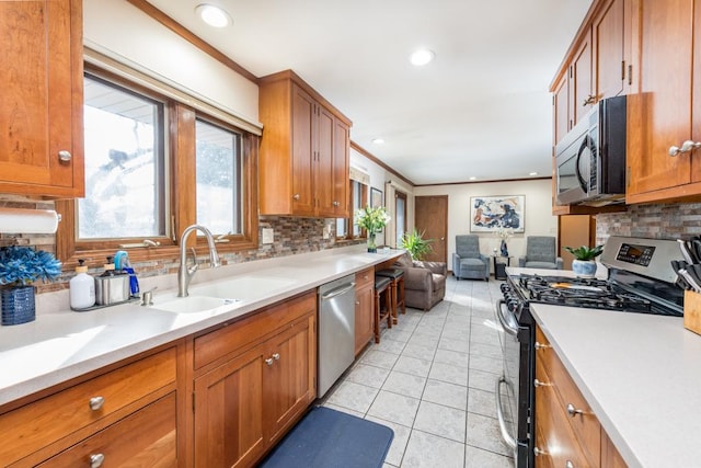 kitchen with appliances with stainless steel finishes, brown cabinetry, a sink, and light countertops