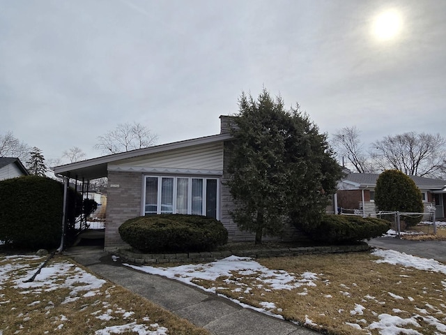 view of front of home with a chimney and brick siding