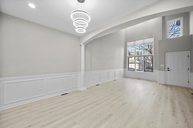 interior space with visible vents, wood finished floors, arched walkways, a chandelier, and ornate columns