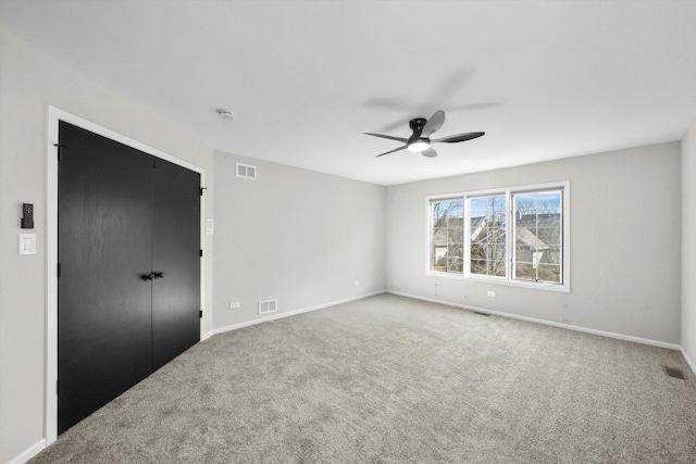 carpeted spare room featuring visible vents, baseboards, and a ceiling fan