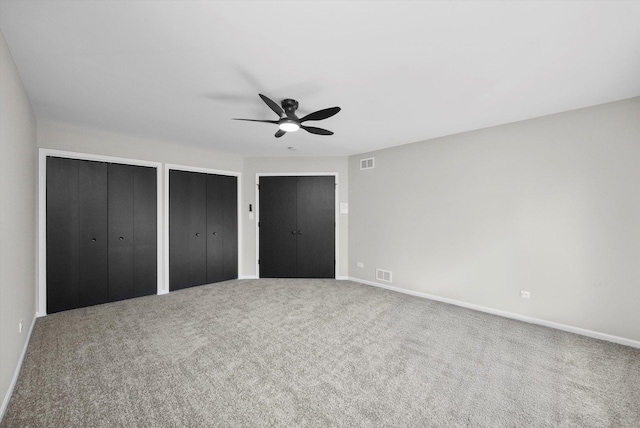 unfurnished bedroom featuring two closets, baseboards, visible vents, and carpet floors