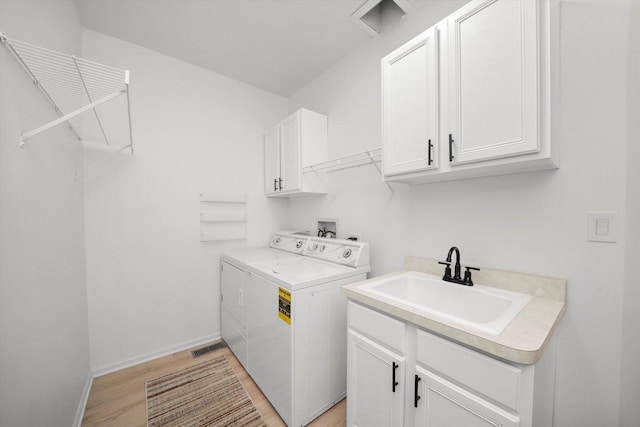 laundry room featuring baseboards, light wood-style floors, cabinet space, independent washer and dryer, and a sink