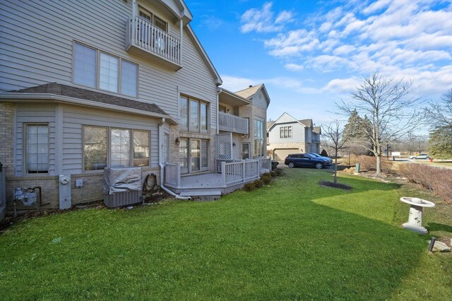 back of house with brick siding, a balcony, and a yard