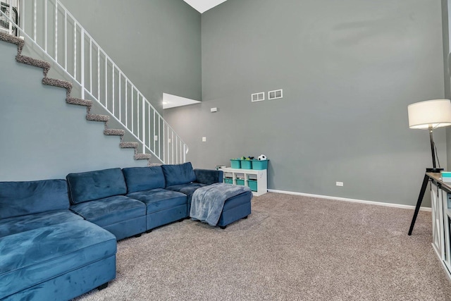 living room featuring carpet floors, visible vents, stairway, and baseboards