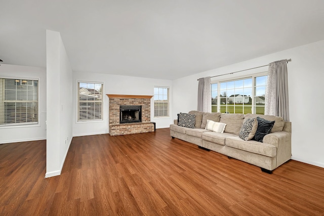 unfurnished living room featuring a brick fireplace, wood finished floors, and baseboards