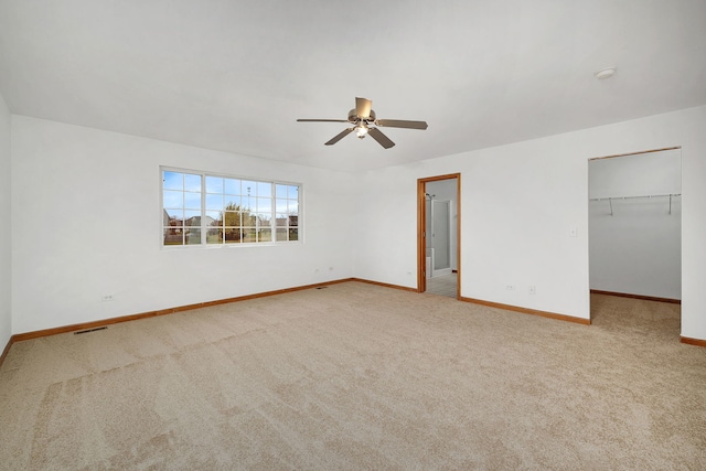 unfurnished bedroom featuring light colored carpet, visible vents, a spacious closet, and baseboards