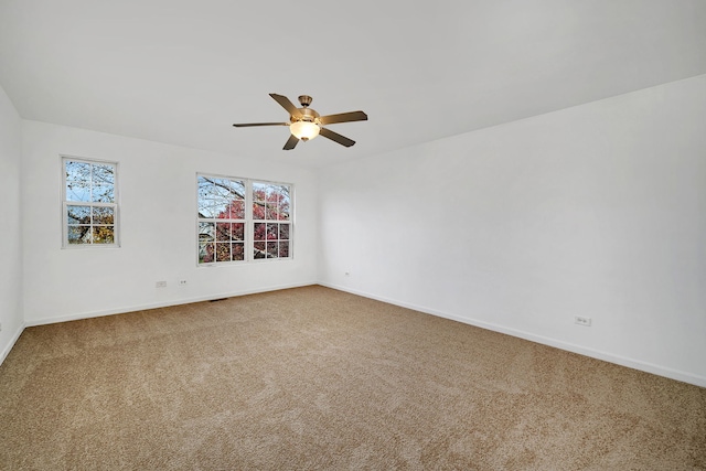 carpeted spare room with ceiling fan and baseboards