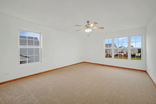 carpeted spare room with baseboards and a ceiling fan