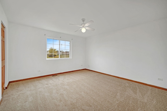 carpeted spare room with ceiling fan, visible vents, and baseboards