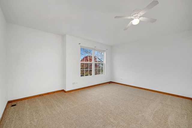 carpeted empty room with visible vents, baseboards, and ceiling fan