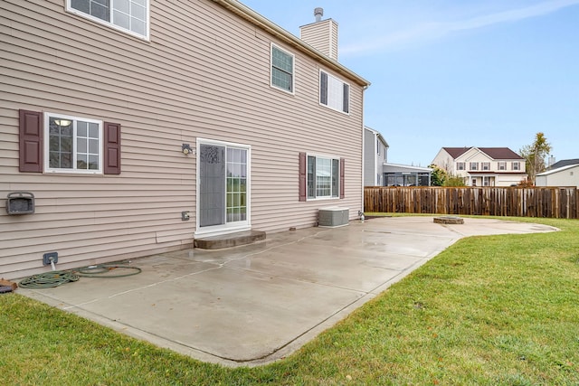 back of property with a chimney, a patio, fence, and a lawn