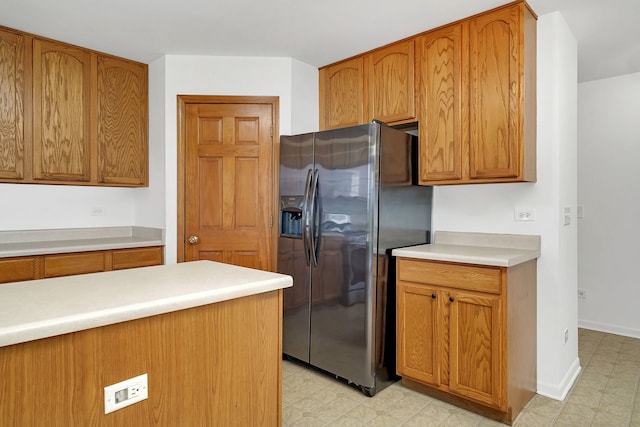 kitchen with light floors, brown cabinetry, light countertops, and stainless steel fridge with ice dispenser